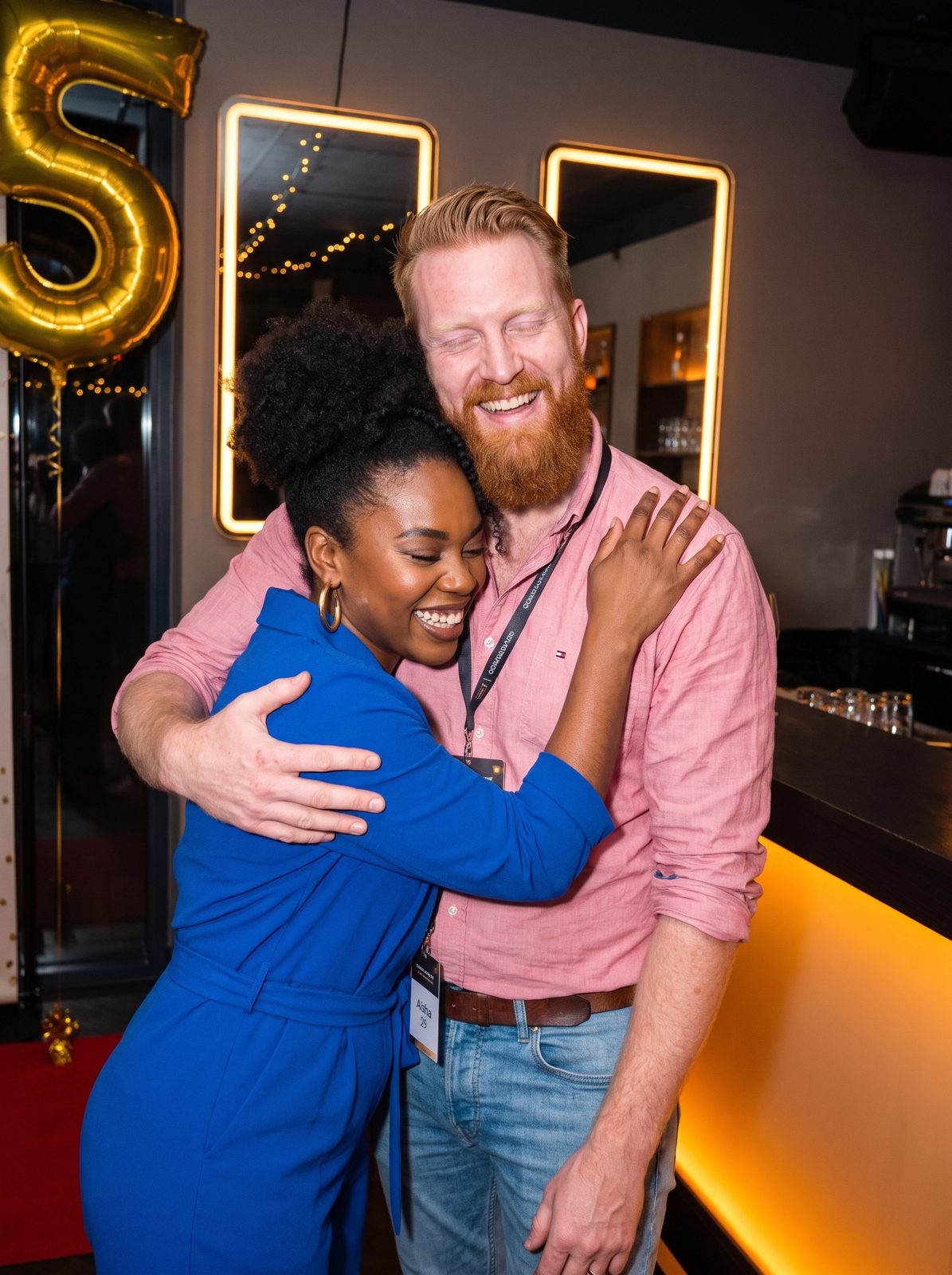 Daan and Aisha hugging and laughing at the bar.