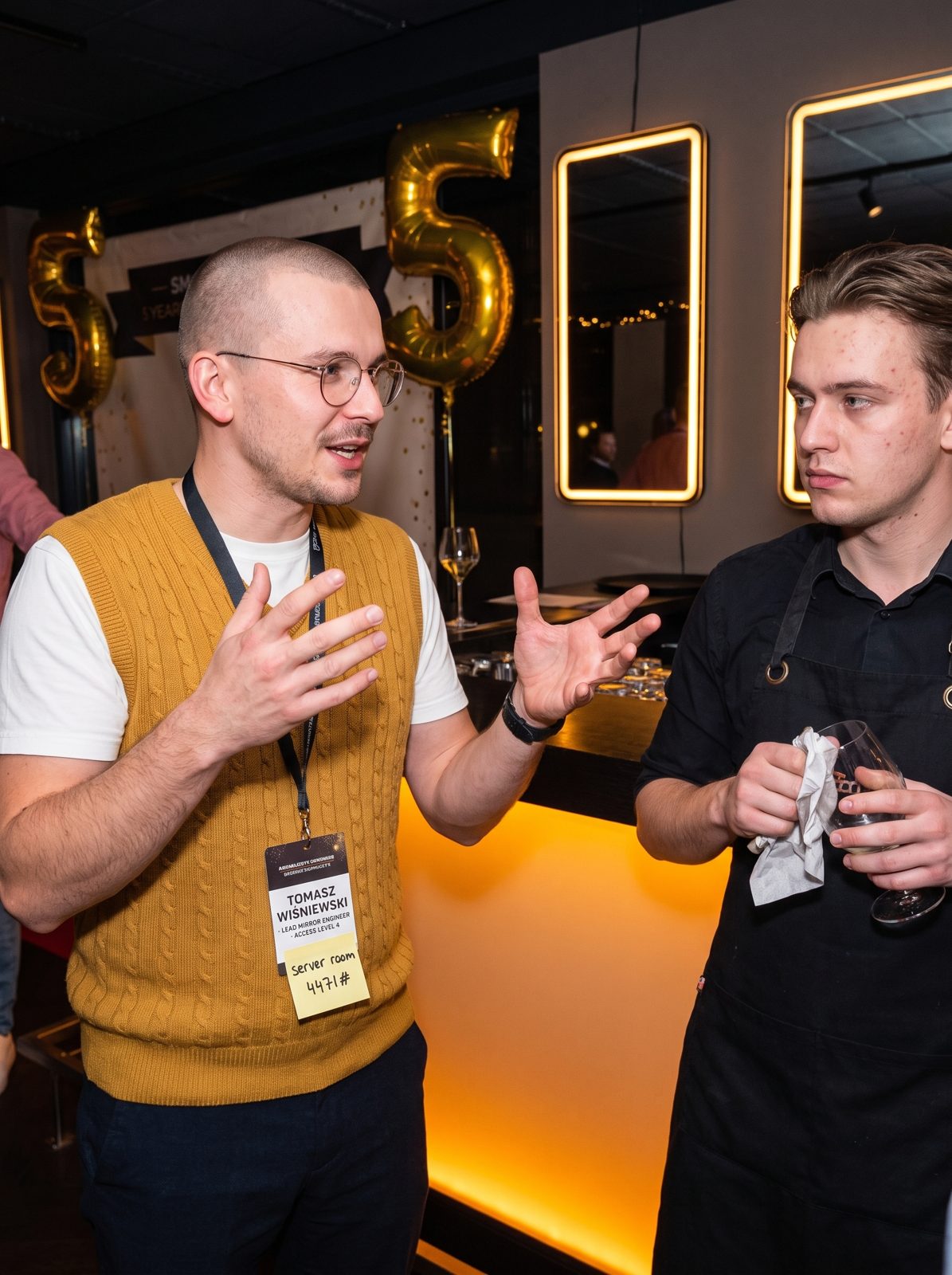 Tomasz talking to a bartender, his access badge and a sticky note with a door code in focus.