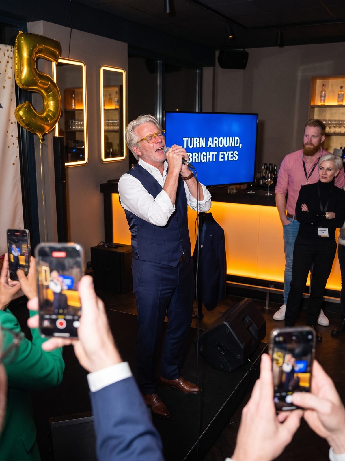 Rutger singing karaoke with his eyes closed in front of a lyrics screen.